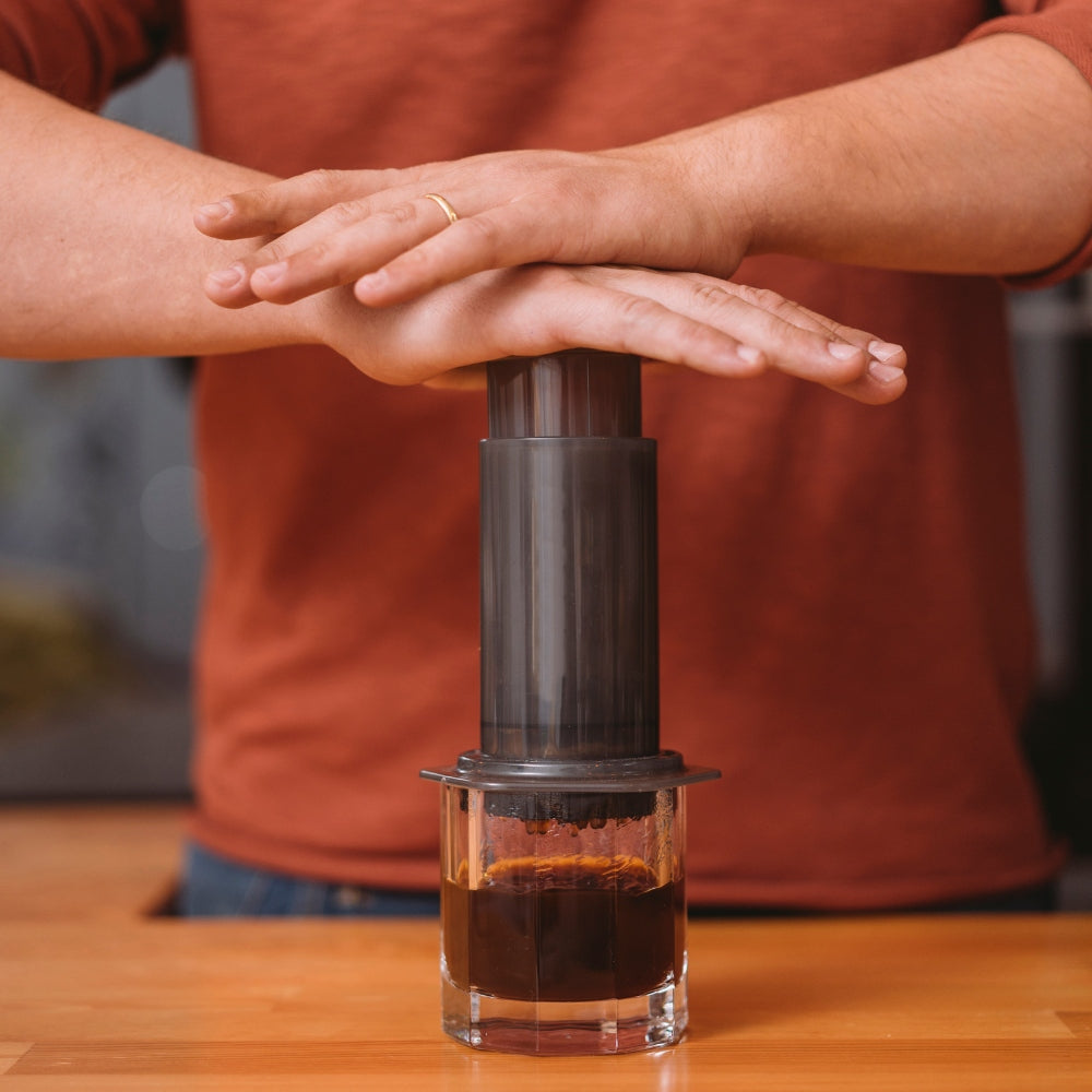 a man pushing down on a aeropress